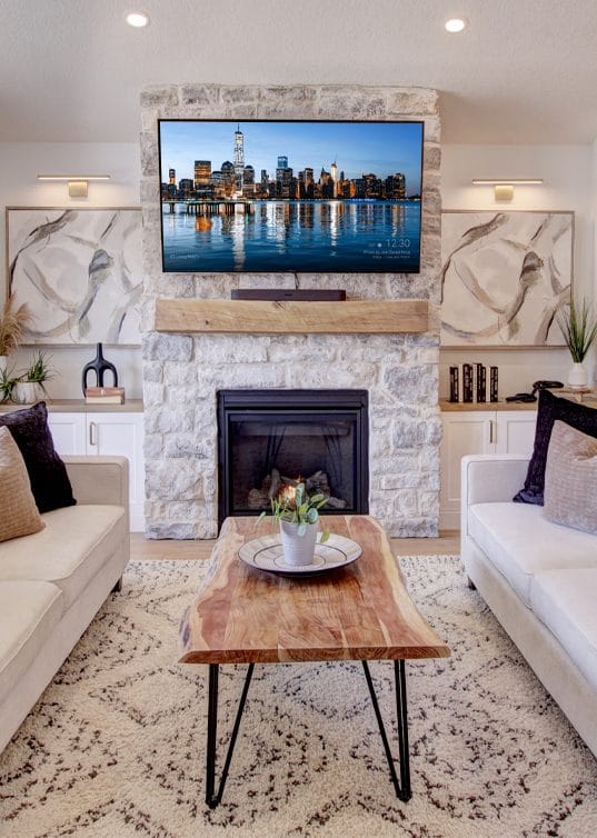 Living room with a stone fireplace, a wall-mounted TV and a live-edge coffee table